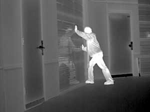 White hot thermal image of a man breaking into a warehouse