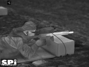 Monochrome white hot FLIR image of a man shooting with a thermal scope mounted on a rifle